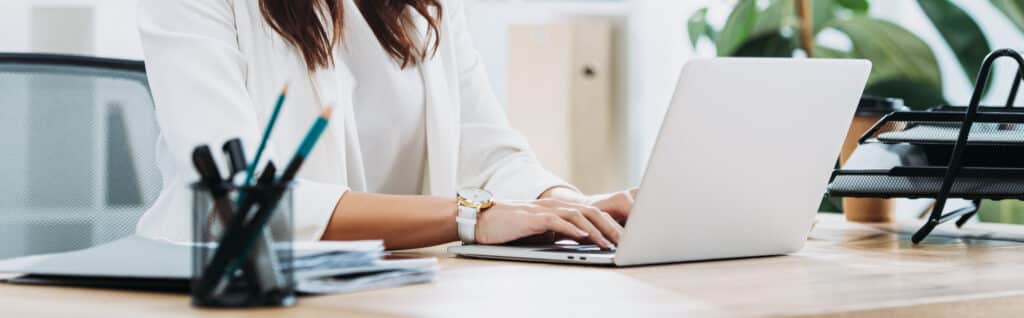 A woman's hands pictured typing on a laptop