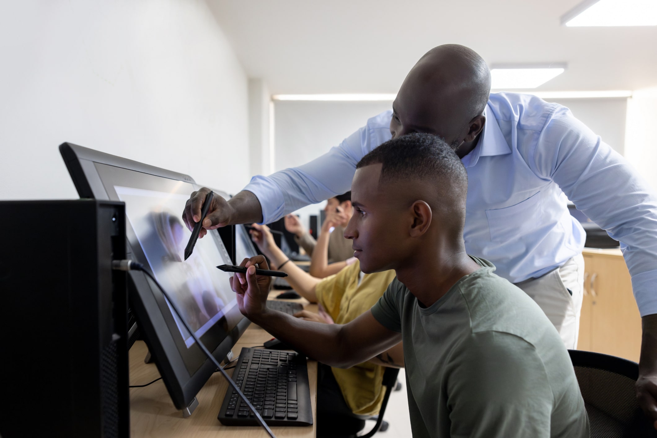 Two people working together on a touchscreen monitor