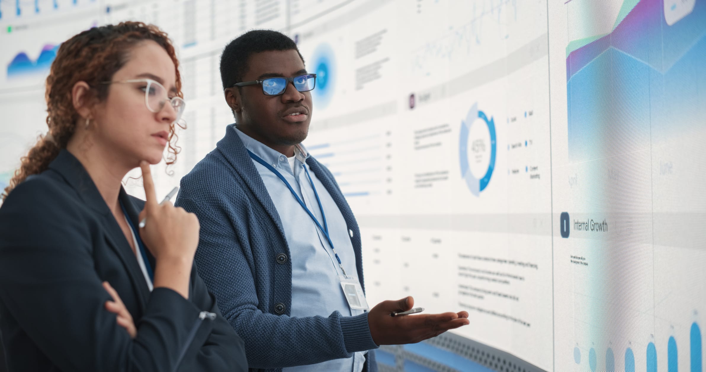 Two coworkers analyzing data on a large screen during a strategy discussion