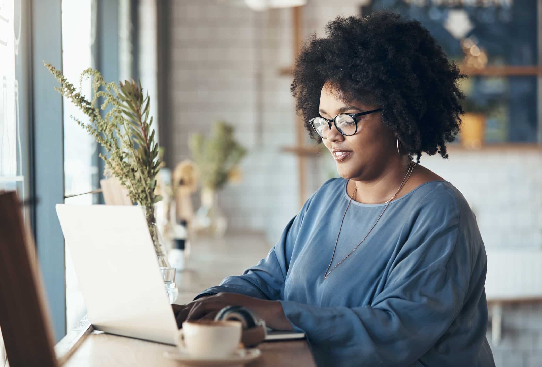A person works on their laptop in a bright and cheerful coffee shop.