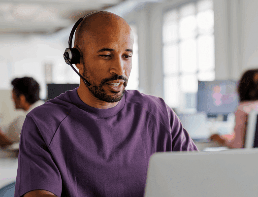 Customer service rep using a laptop and headphones in front of a laptop to represent Microsoft’s team using our product for customer support training.