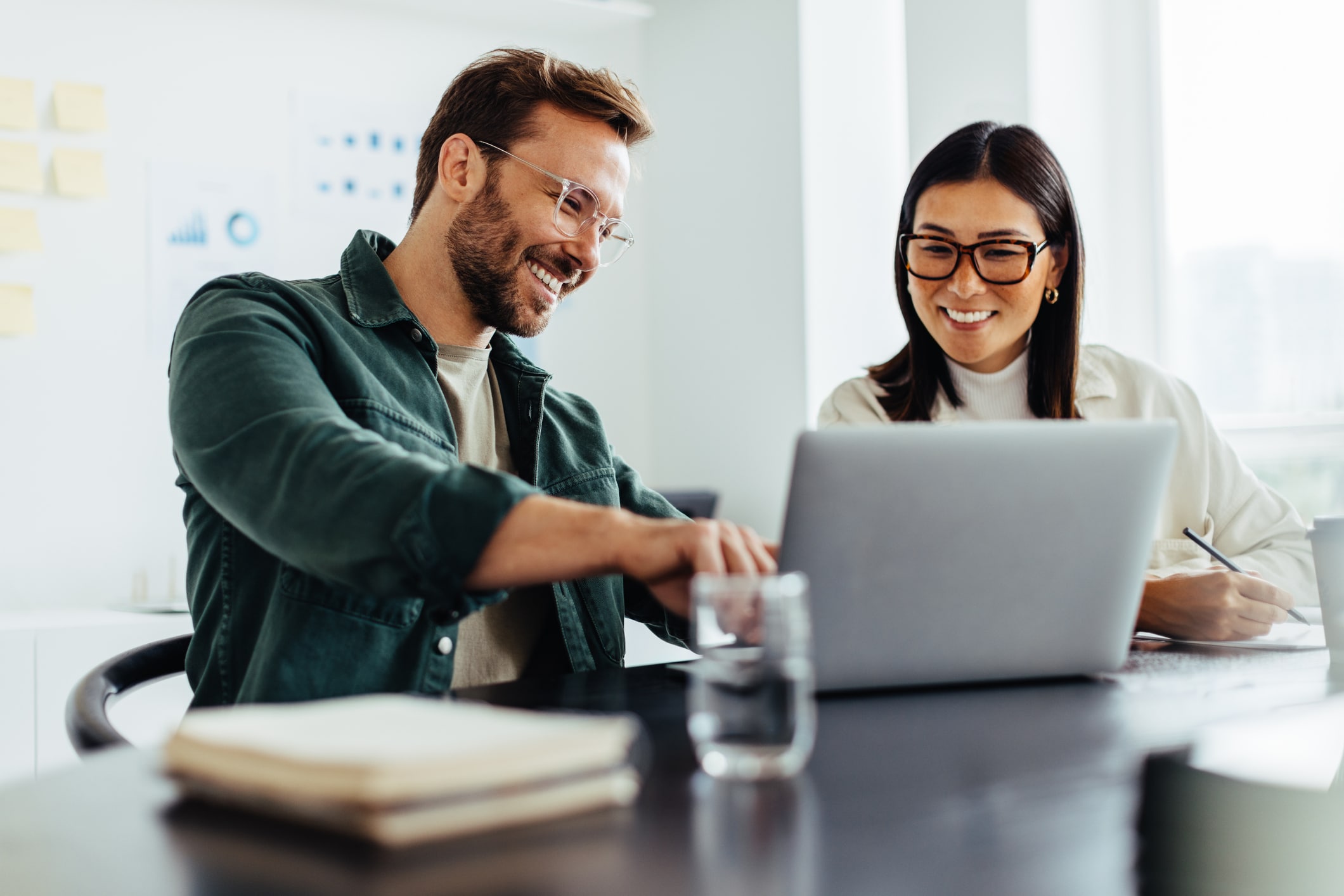 Two business people using a laptop together while sitting in a meeting