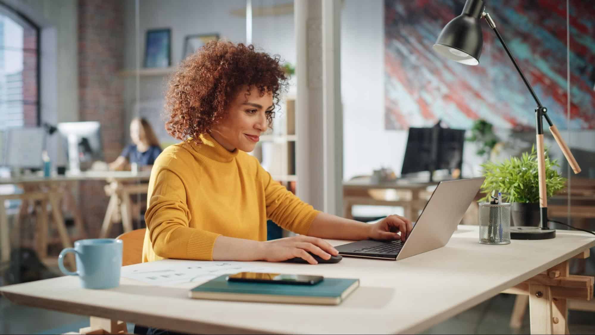 Smiling woman sitting at a desk and working on a laptop