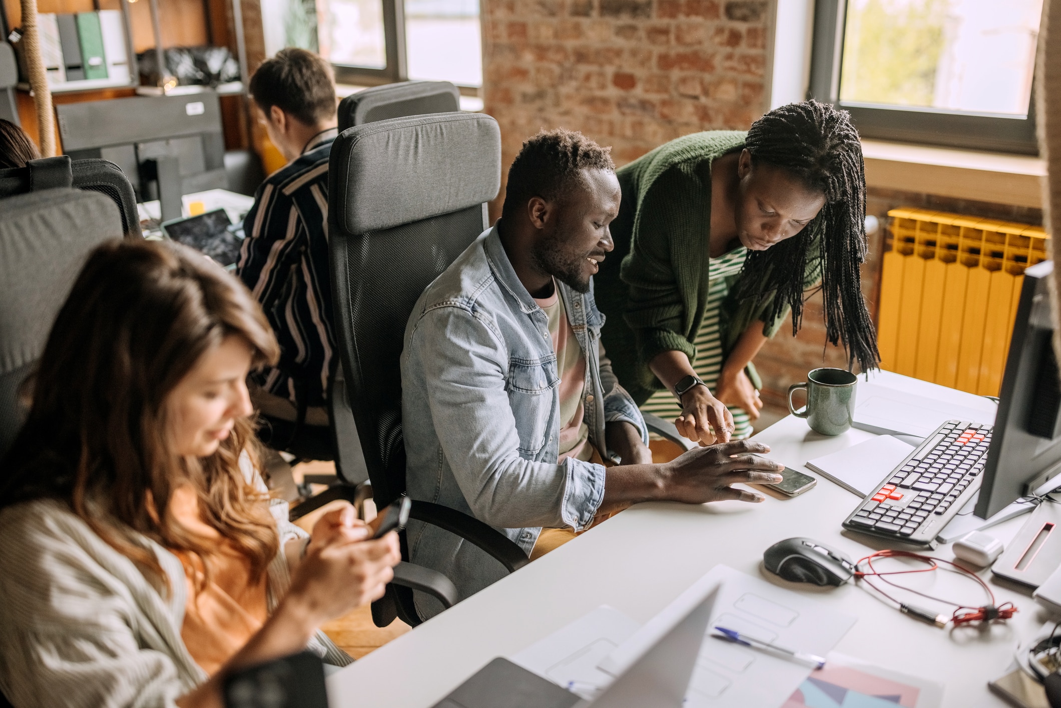 People sitting along a big table and looking at their devices