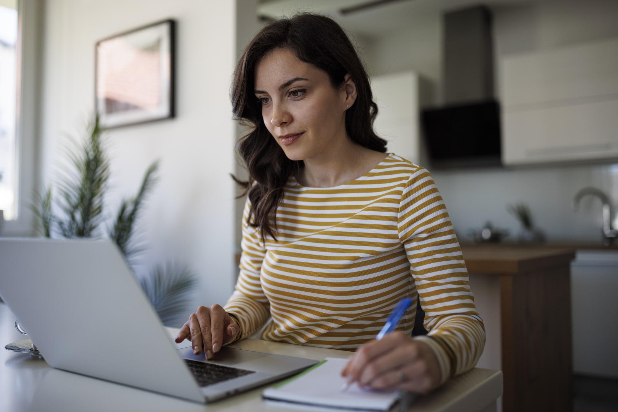 Person taking an e-learning course and writing notes in a notebook