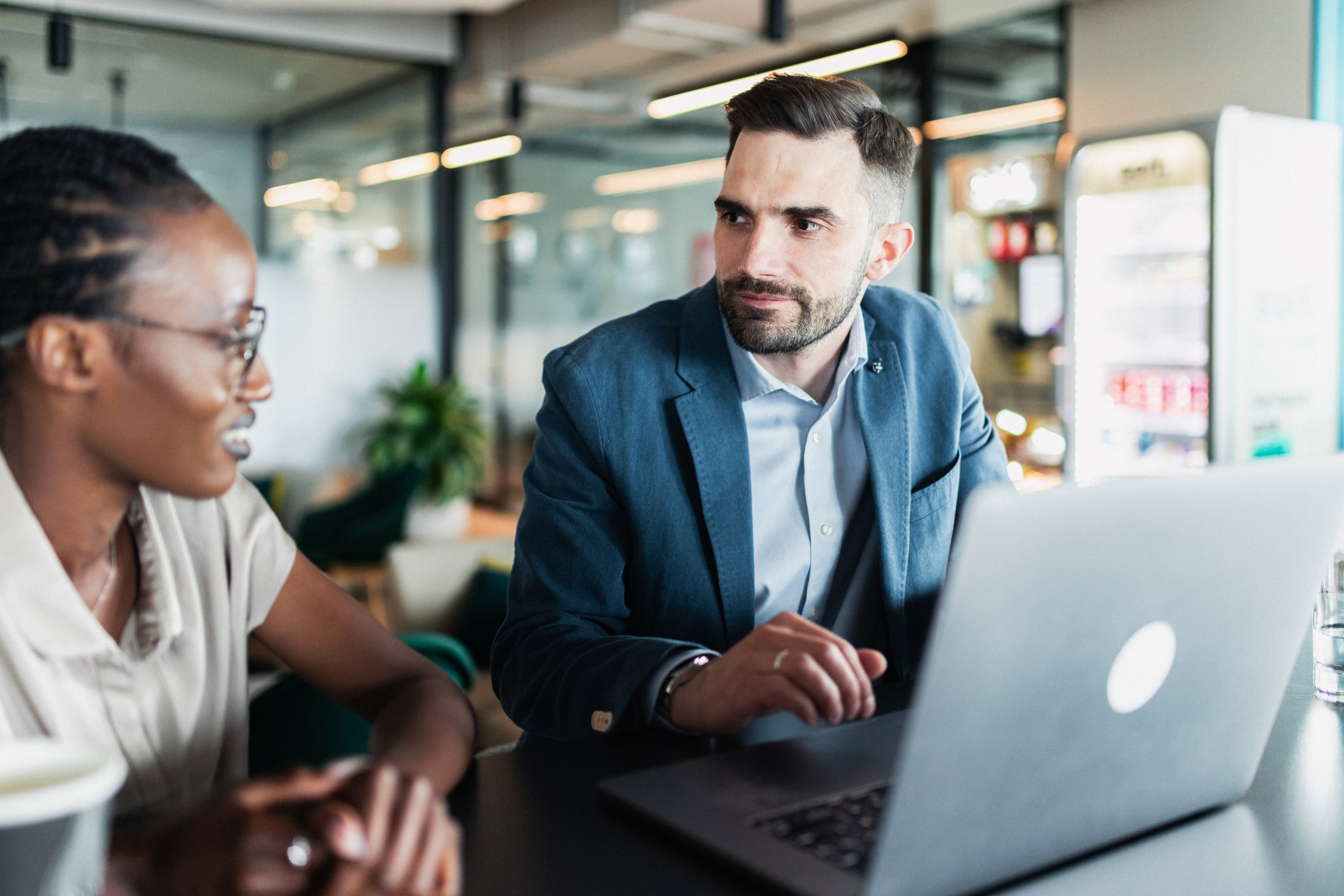 Two professionals collaborating on a project while analyzing information on a laptop