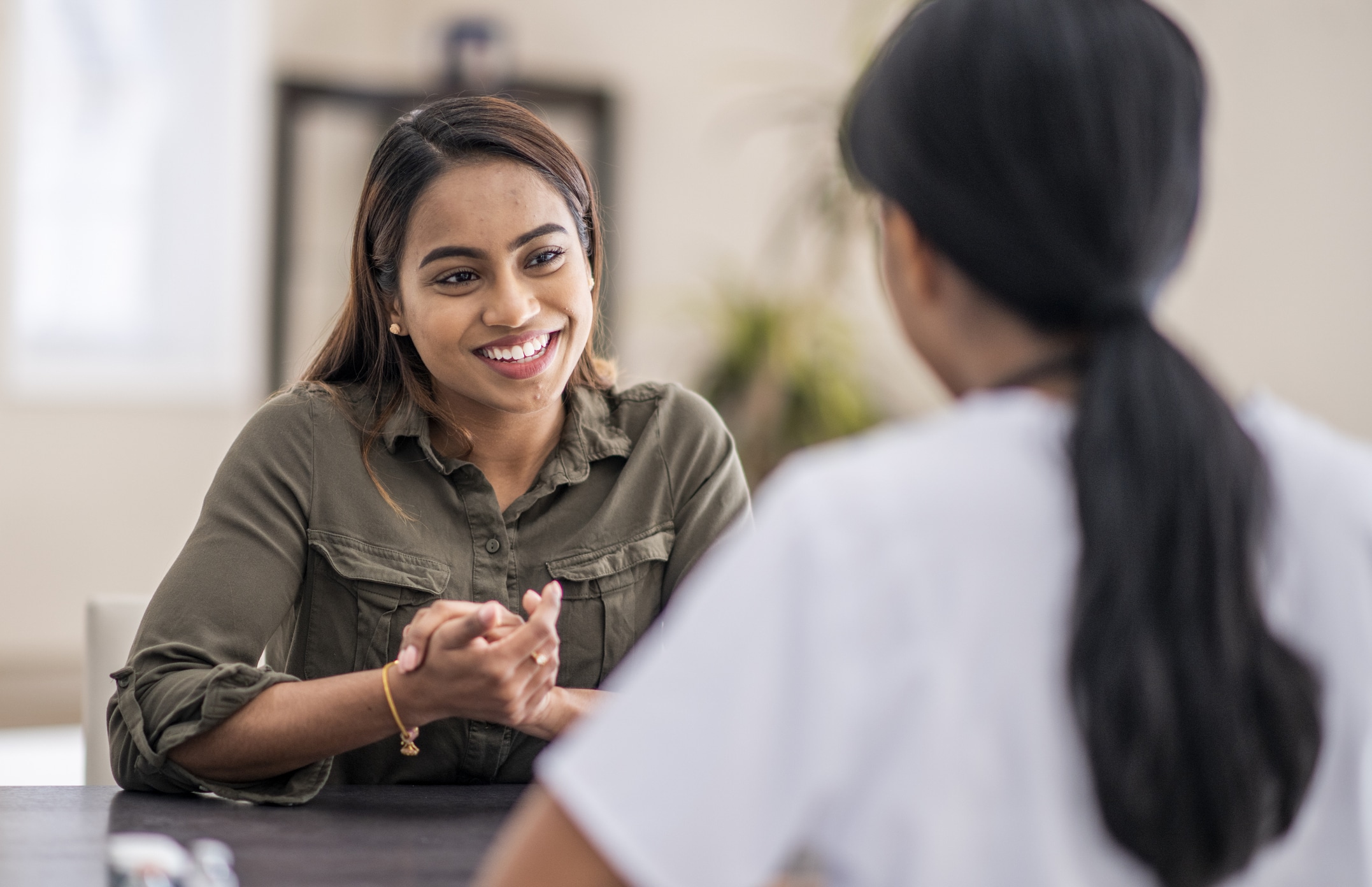 Two people smiling and having a conversation at a table