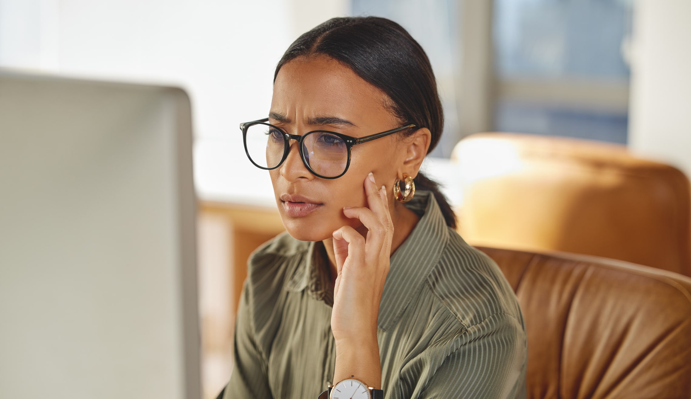 Employee looking confused while working on a computer in an office