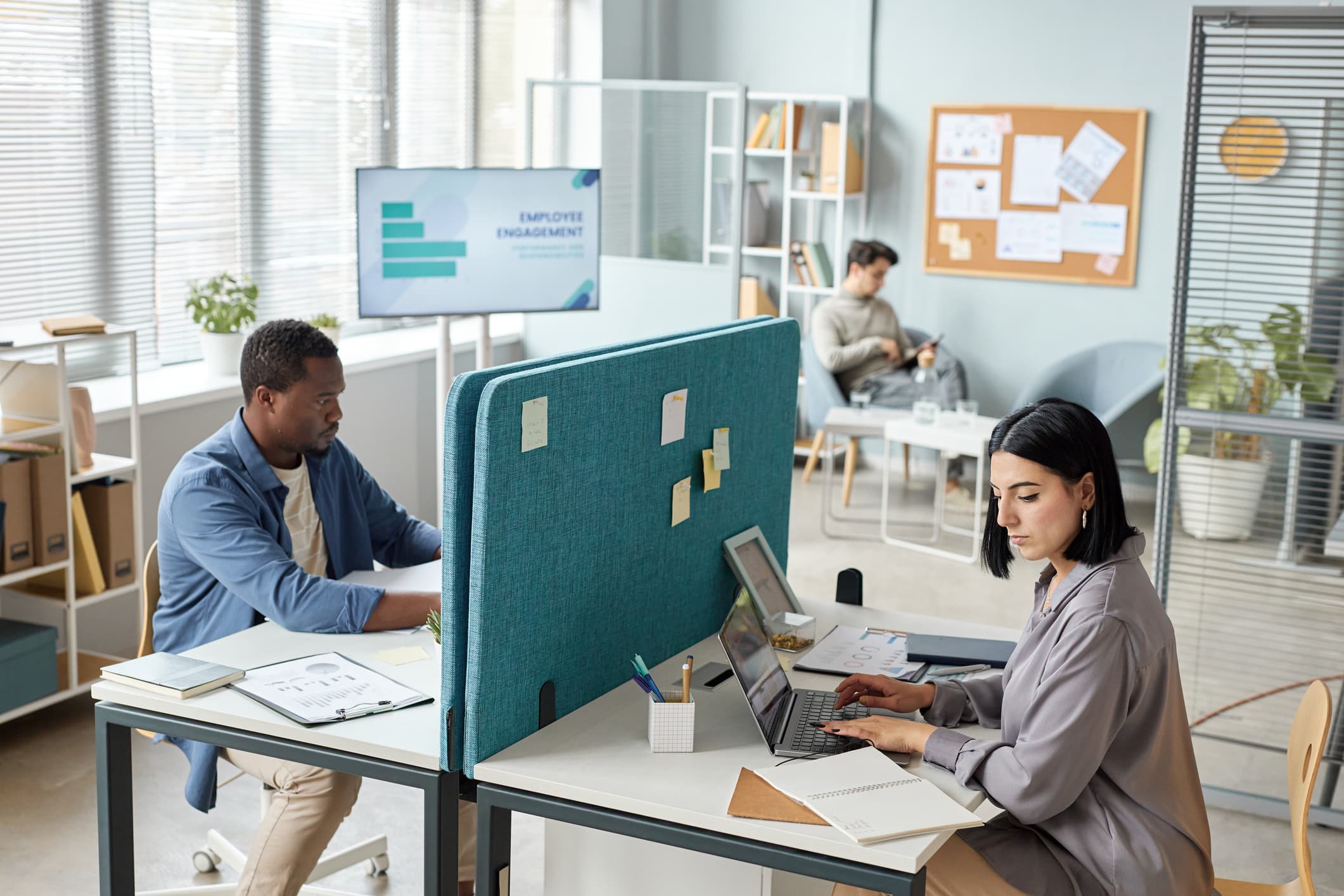 Two people working in an office, separated by a partition wall