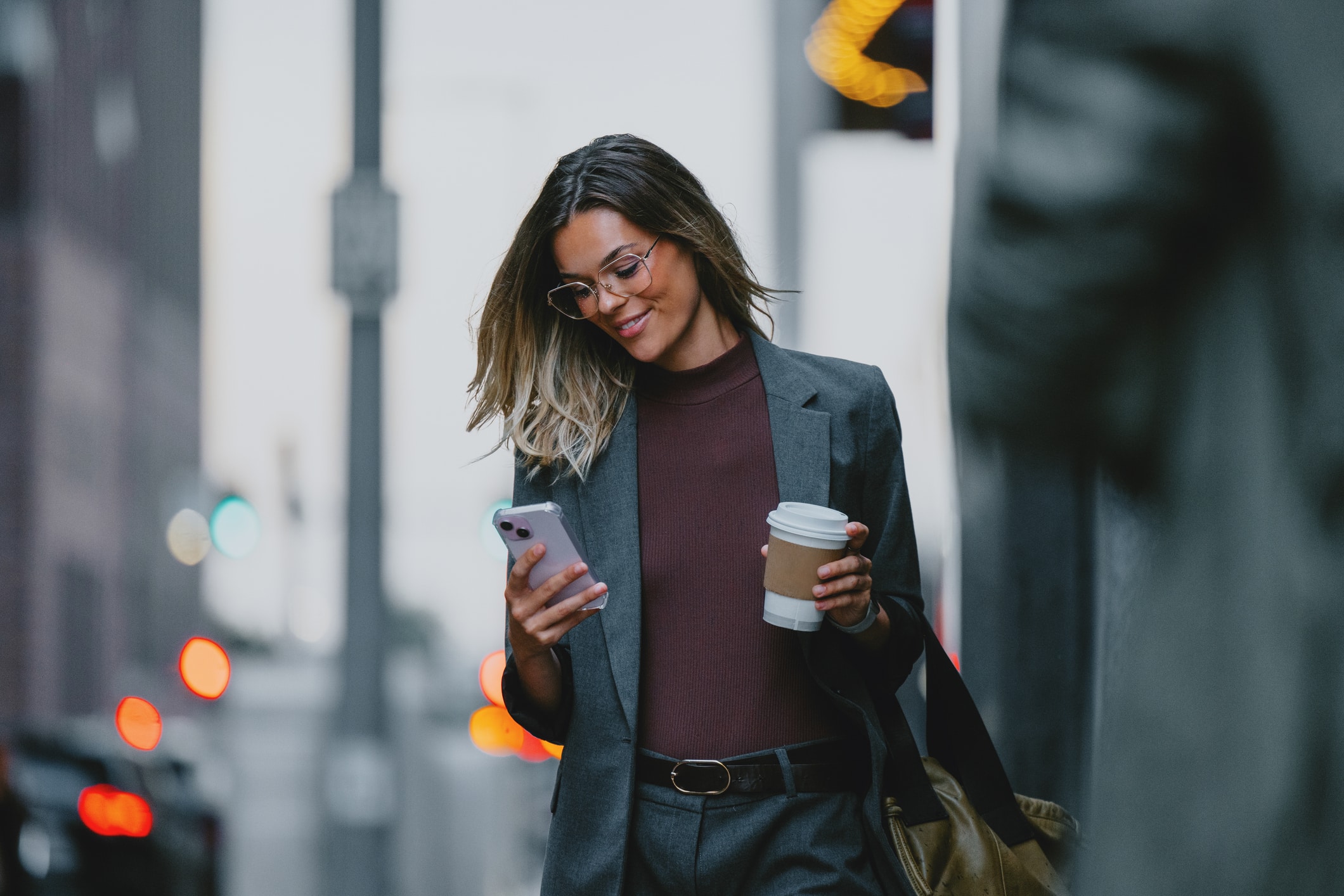 Businessperson walking while looking at their phone in a city environment