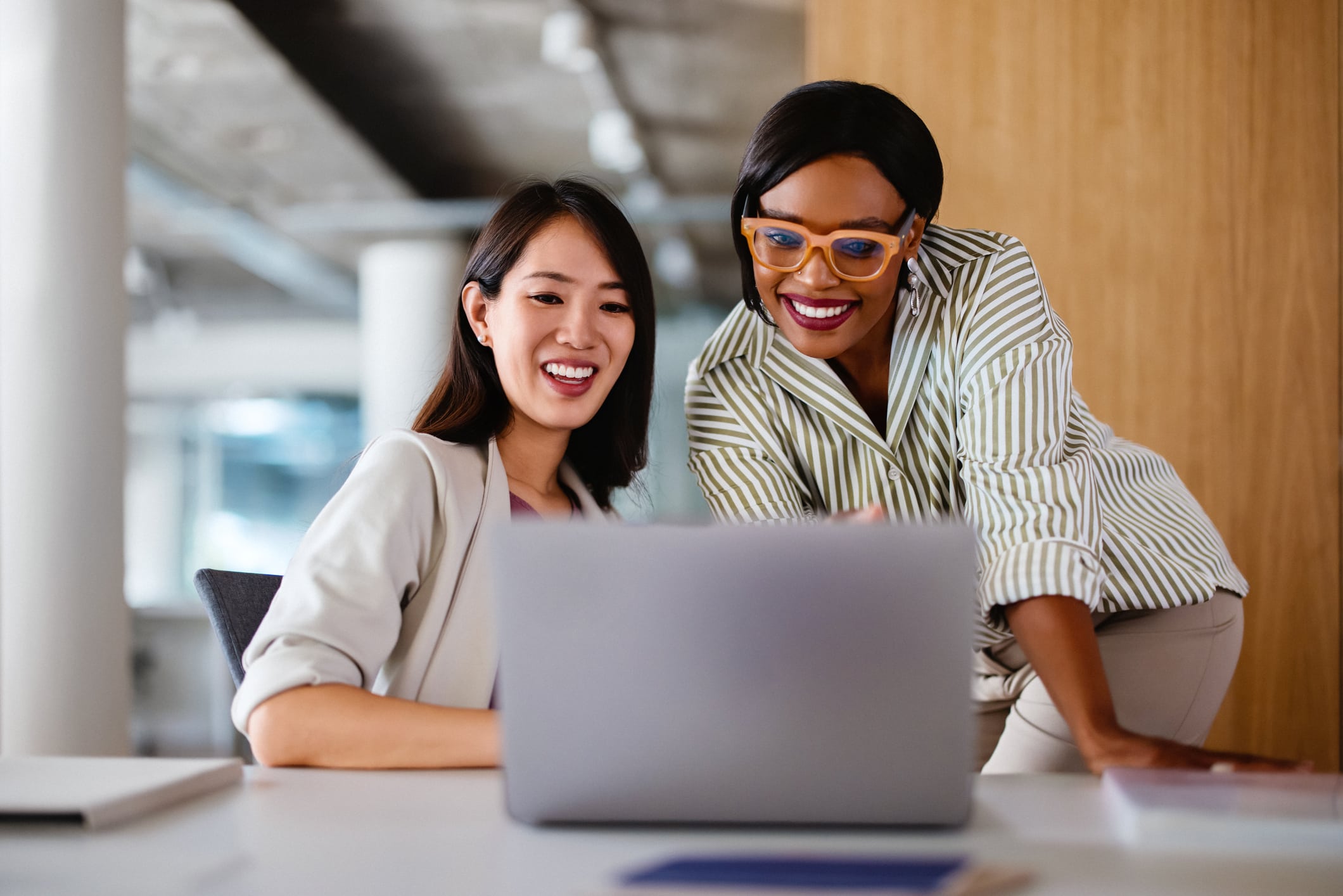 Two professionals discussing work on a laptop, demonstrating teamwork and collaboration in a modern office setting.