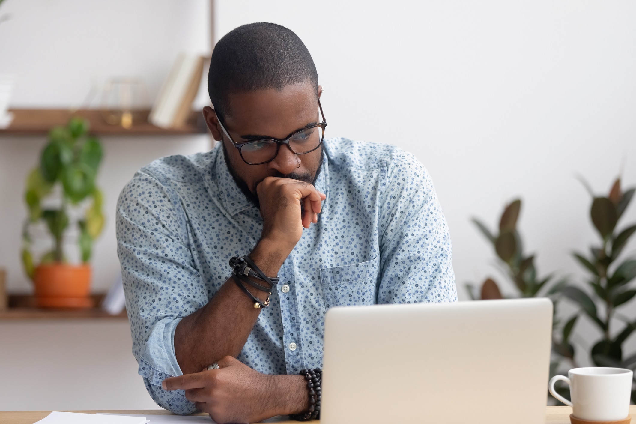 A man looks puzzled while looking at a laptop in an office.