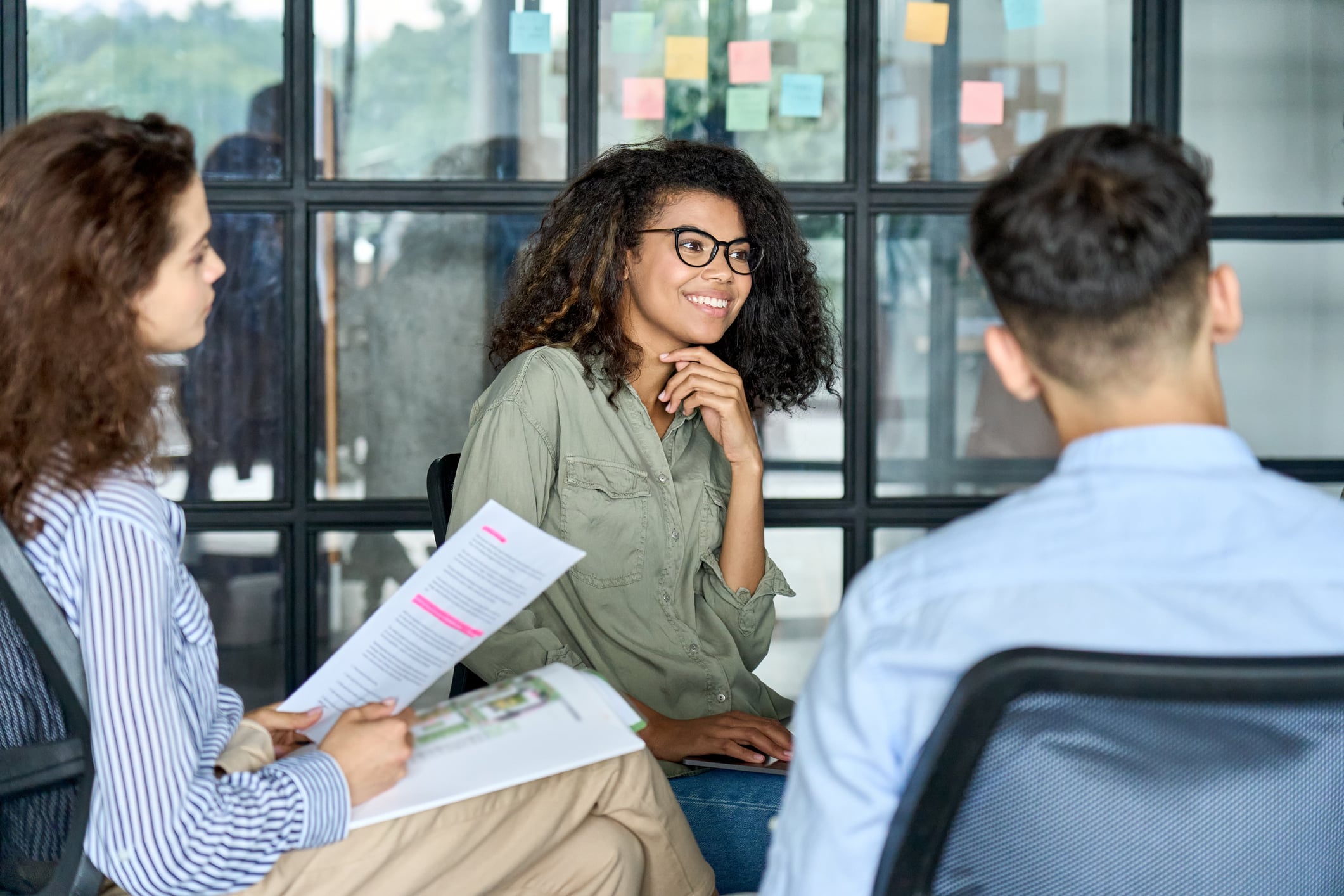 Person smiling while sitting in a meeting with colleagues