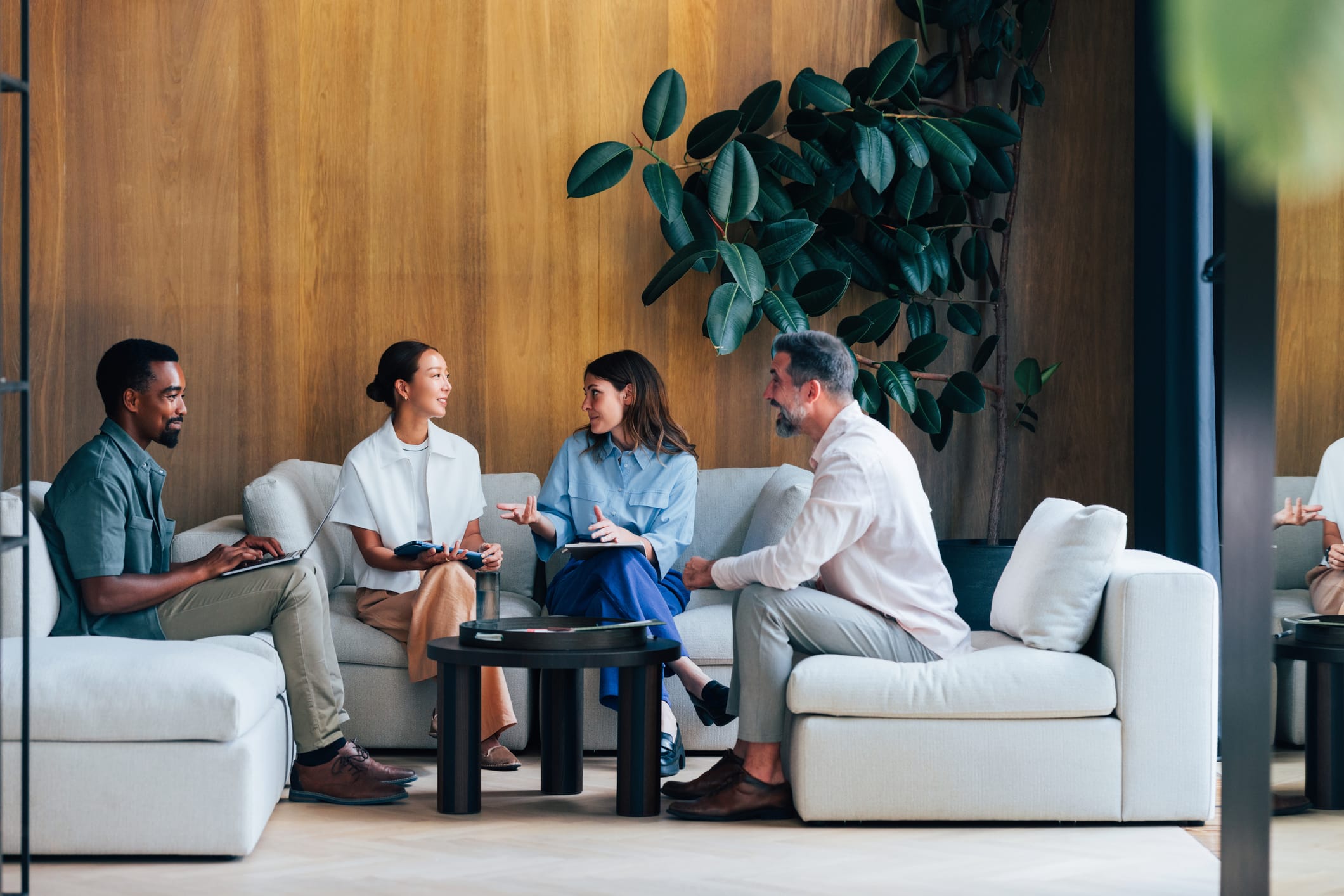 A group of four professionals engaging in a collaborative discussion in a stylish, modern lounge area
